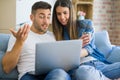 Young couple moving to a new home relaxing sitting on the sofa using computer laptop, smiling happy for moving to new apartment Royalty Free Stock Photo