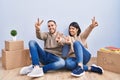 Young couple moving to a new home smiling with tongue out showing fingers of both hands doing victory sign Royalty Free Stock Photo