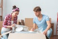 Young couple moving to new place sitting near box unpacking dishes smiling happy Royalty Free Stock Photo