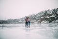 Young couple with mug of tea walks on ice of frozen lake. Royalty Free Stock Photo