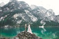 Young couple near lake Karersee, Italy. Holding hands at the stone at lake