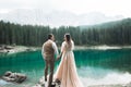 Young couple near lake Karersee, Italy. Holding hands at the stone at lake