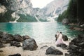 Young couple near lake Karersee, Italy. Holding hands at the stone at lake