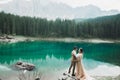 Young couple near lake Karersee, Italy. Holding hands at the stone at lake