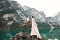 Young couple near lake Karersee, Italy. Holding hands at the stone at lake