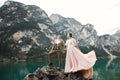 Young couple near lake Karersee, Italy. Holding hands at the stone at lake