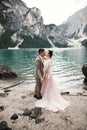 Young couple near lake Karersee, Italy. Holding hands at the stone at lake