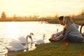 Young couple near lake with swans. Perfect place for picnic Royalty Free Stock Photo