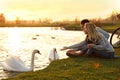 Young couple near lake with swans. Perfect place for picnic Royalty Free Stock Photo
