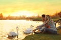 Young couple near lake with swans. Perfect place for picnic Royalty Free Stock Photo