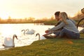 Young couple near lake with swans. Perfect place for picnic Royalty Free Stock Photo