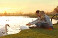 Young couple near lake with swans. Perfect place for picnic