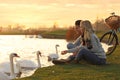 Young couple near lake with swans. Perfect place for picnic Royalty Free Stock Photo