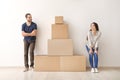 Young couple near tower made of boxes indoors. Moving into new house