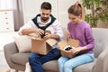 Young couple opening parcels on sofa in room Royalty Free Stock Photo