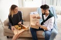 Young couple opening parcels on sofa in room Royalty Free Stock Photo