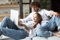 Young couple ordering online, looking in laptop while sitting on couch