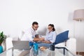 Young couple organizing their economy, taking notes on the couch in the living room at home, with laptop and money on the table.