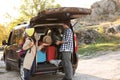 Young couple packing camping equipment into car trunk outdoors. Royalty Free Stock Photo