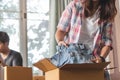 Young couple packing cloth into cardboard box prepare to move out to new location