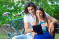 Young couple on the park bench with credit card and tablet Royalty Free Stock Photo