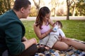 young couple in the park sitting on the grass while the mother feeds her baby Royalty Free Stock Photo