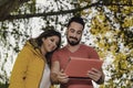 Young couple in the park with a tablet. girl in yellow coat and boy in red shirt Royalty Free Stock Photo