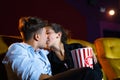 Young couple people kissing at movie theater. In hand holding snack bucket and throw popcorn around the seat Royalty Free Stock Photo