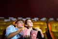 Young couple people watching movie feeling scary and frightening at movie theater. In hand holding snack bucket and throw popcorn Royalty Free Stock Photo