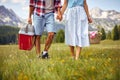 Young couple with picnic baskets holding hands and walking on green meadow. Picnic time, couple in nature.  Fun, togetherness, Royalty Free Stock Photo