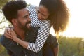 Young couple piggybacking outdoors, head and shoulders Royalty Free Stock Photo