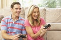 Young Couple Playing Computer Game On Sofa At Home Royalty Free Stock Photo