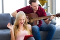 Young couple playing guitar with tablet at home. Royalty Free Stock Photo