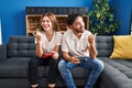 Young couple playing video game holding controller at home pointing thumb up to the side smiling happy with open mouth Royalty Free Stock Photo