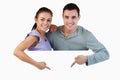 Young couple pointing at advertisement below them Royalty Free Stock Photo