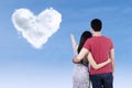 Young couple pointing at heart clouds Royalty Free Stock Photo