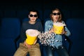 Young couple with popcorn watching interesting movie on their date in cinema. World cinema day concept Royalty Free Stock Photo