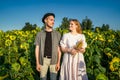 young couple poses for camera, looks at each other, smiles in sunflower field Royalty Free Stock Photo