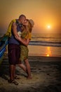 Young couple posing against sea at sunset. Guy and girl fooling and grimace near the old wooden boat on the ocean coast Royalty Free Stock Photo