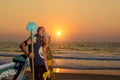 Young couple posing against sea at sunset. Guy and girl fooling and grimace near the old wooden boat on the ocean coast Royalty Free Stock Photo