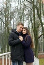 Young couple posing near the railing of a foot bridge in the park. Late autumn, fog Royalty Free Stock Photo