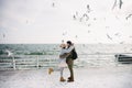 young couple posing on winter quay at sea