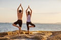 Young couple practicing yoga on the beach at sunset Royalty Free Stock Photo