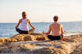 Young couple practicing yoga on the beach at sunset Royalty Free Stock Photo