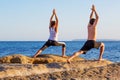 Young couple practicing yoga on the beach at sunset Royalty Free Stock Photo