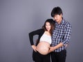 Young couple: pregnant mother and happy father on gray backgroun Royalty Free Stock Photo