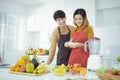 Young couple preparing a fruits smoothie in kitchen at home, healthy lifestyle. Royalty Free Stock Photo