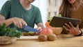 Young couple preparing ingredients for making healthy vegan salad with fresh vegetables in kitchen. Royalty Free Stock Photo