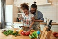 Young couple preparing a meal together in the kitchen. Italian man, chef cook helping his girlfriend to use hand blender Royalty Free Stock Photo