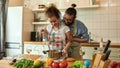 Young couple preparing a meal together in the kitchen. Italian man, chef cook helping his girlfriend to use hand blender Royalty Free Stock Photo